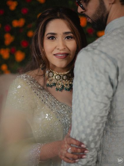 A beautiful, intimate portrait of the bride looking over her partner's shoulder during their Mehendi ceremony. The soft focus and her gentle smile create a warm and loving moment.