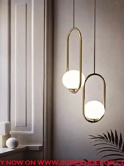 These lustrous insignia hanging lights feature a milky white globe suspended within an elegant antique brass loop. They are perfect for hanging in pairs or clusters to create a sophisticated and modern lighting statement.