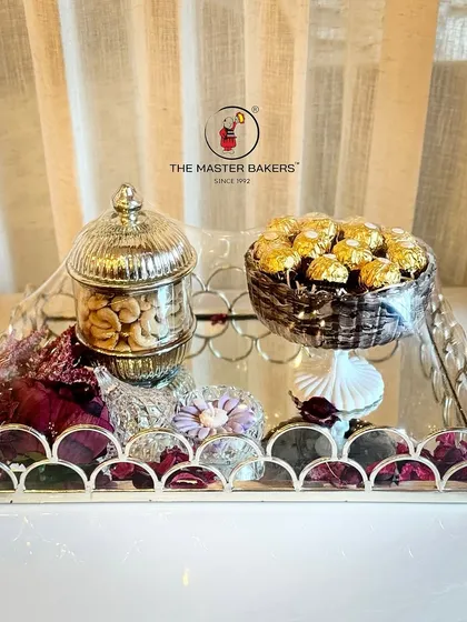 Our bespoke gifting service allows you to create a truly personal present. This luxury hamper features a decorative silver tray holding assorted chocolates, premium cashews in a crystal jar, and a calming scented candle, making it a complete sensory experience.