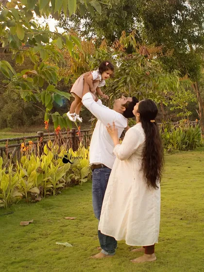 Flying high with dad! This joyful, dynamic shot captures a classic moment of play between a father and his daughter in a beautiful outdoor park setting.