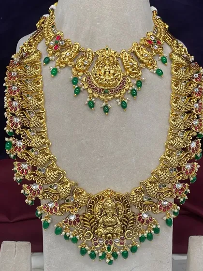 Here you can see the fine details of one of my antique bridal sets. This rental piece features Goddess Lakshmi motifs, peacock designs, and is studded with Kempu stones and green beads, available for your wedding in Bangalore.