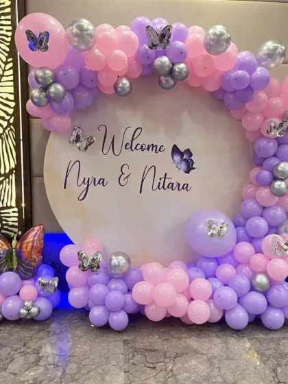 Welcome home the new princess, or two, with this beautiful butterfly-themed decoration. A circular backdrop personalized with the babies' names is framed by a pink, purple, and silver balloon arch with delicate butterfly accents.
