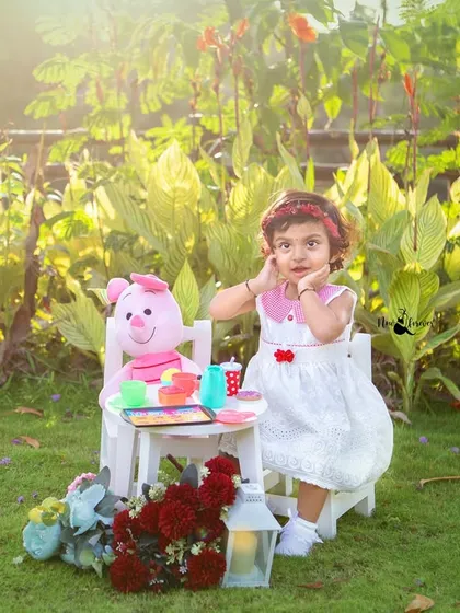 A whimsical outdoor tea party for a sweet two-year-old. The soft, natural light and lush green background create a dreamy setting for capturing her playful spirit.