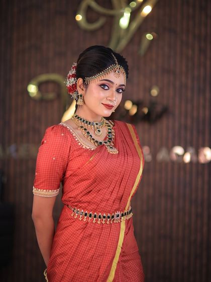 Model Swetha in a red checked silk saree. This traditional drape is perfect for showcasing classic South Indian bridal looks for catalogues or campaigns.