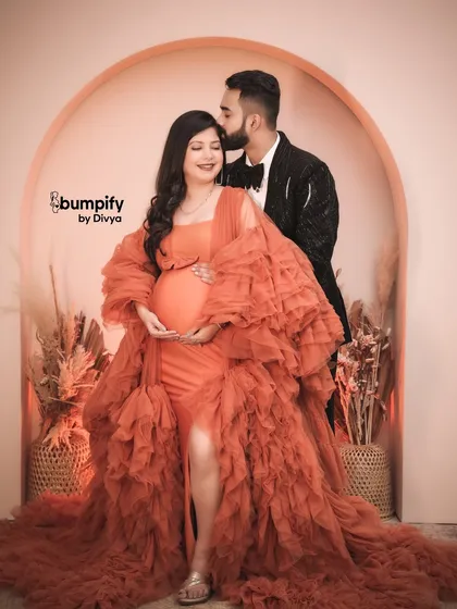 A sweet kiss from the dad-to-be makes this a perfect couple's portrait. The love and excitement between them is palpable in this beautiful studio shot.