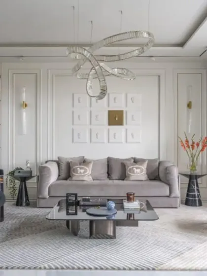 We create luxurious living rooms with a focus on comfort and high-end finishes. This space features a plush grey velvet sofa, a unique crystal chandelier, and elegant wall molding for a timeless look.