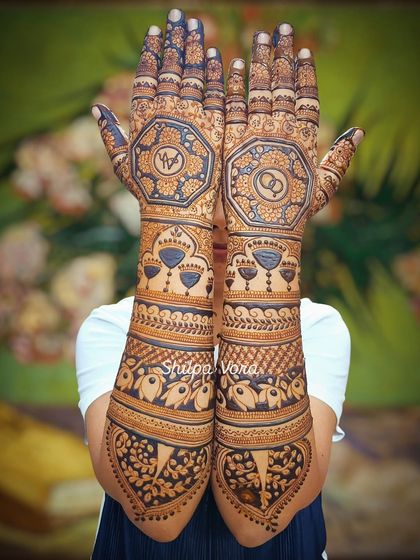 Full arm mehndi for Karwa Chauth, featuring engagement rings inside a geometric pattern. A perfect design for a bride-to-be celebrating the festival.