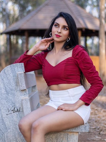 A relaxed and elegant portrait taken in a park. The model is seated on a stone bench, creating a look that is both stylish and grounded in the natural beauty of the outdoors.