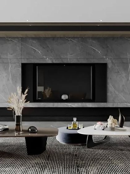 We designed this living room for a cinematic experience, featuring a dark, full-wall entertainment unit. The unit includes a marble-finish back panel and integrated bookshelves, creating a sophisticated and immersive environment.