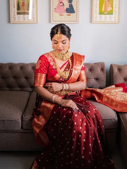 A bride seated gracefully, wearing a complete set of antique gold-finish temple jewellery. The layered necklaces and kamarbandh create a look of pure opulence.
