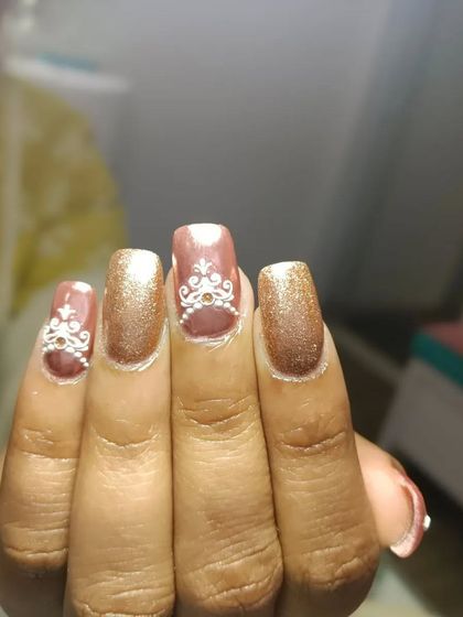 A close-up of the detailed white henna-inspired art on these rose gold bridal nails. The fine lines and patterns are drawn by hand to create a truly unique and coordinated look for the wedding.