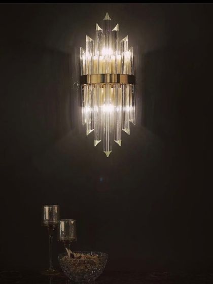 A crystal wall sconce with a classic, torch-like design. This fixture adds a touch of timeless glamour to a dark, dramatic wall.