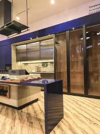 A view of our showroom kitchen, featuring a bold blue finish, an elegant island, and extensive glass-fronted storage.