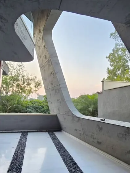 A unique, organically shaped cutout in the concrete wall frames the sky and trees like a living painting. This design feature turns a simple balcony into a contemplative space connected to the outdoors.
