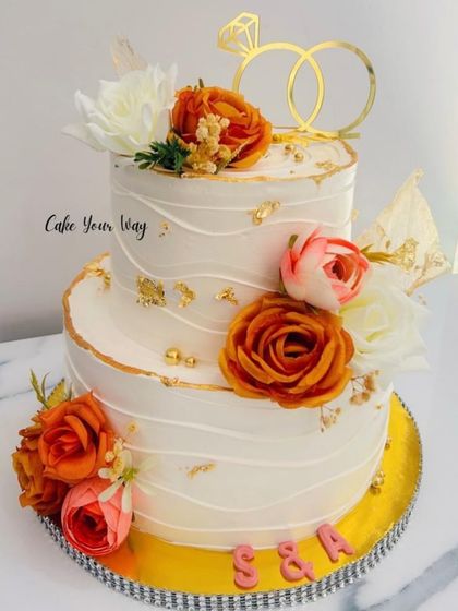 Baked with love, decorated with dreams. A beautiful two-tier engagement cake with orange and white flowers.
