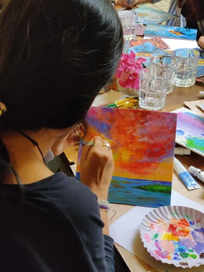 Getting lost in the flow of painting. This participant is creating a vibrant sunset over the ocean, blending colors like a pro.