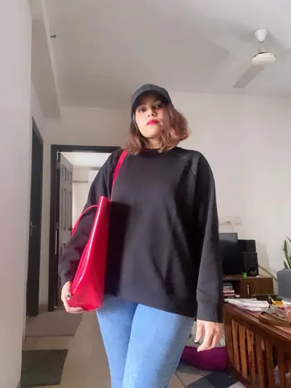 My official welcome to winter. A cozy black sweatshirt, comfortable jeans, and a baseball cap are my essentials. I add a pop of color with a bright red tote bag to liven up a gray day.
