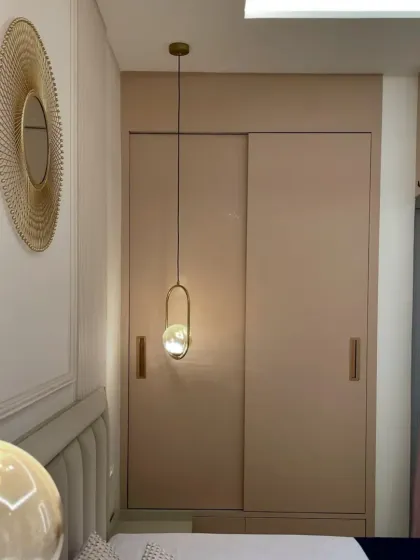 A close-up of the bedroom's details, including the elegant pendant lighting and the smooth, handleless sliding wardrobe. We use high-quality PU and Laminate finishes for a distinctive look.