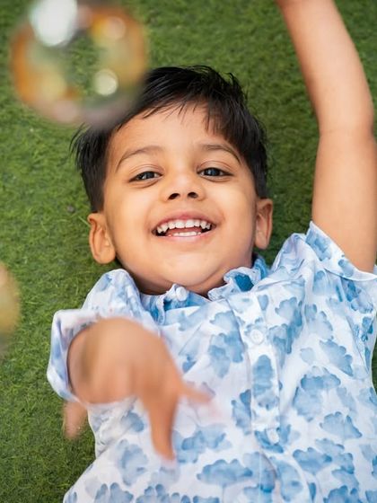 A joyful, high-angle shot of the birthday boy playing with bubbles. This perspective captures his unrestrained happiness and the fun atmosphere of the party.