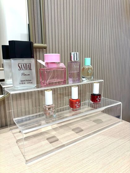 We use simple tools like this tiered acrylic riser to create elegant displays for perfumes and nail polishes. It elevates the items, making it easy to see everything on your vanity.