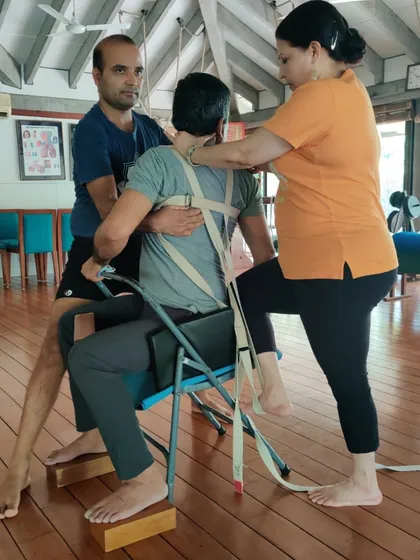 Here, we are using a chair, blocks, and a belt to help a student with a supported spinal twist. This intricate setup ensures the twist originates from the correct place, providing therapeutic benefits for the spine and internal organs.