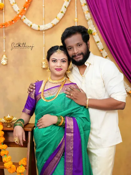 A classic portrait of a couple ready for a traditional ceremony. The vibrant green and purple saree, paired with festive decor, creates a joyful and culturally rich image.