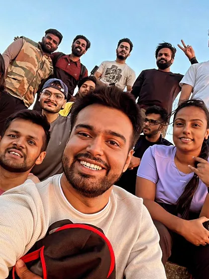 A happy group selfie at the top of Skandagiri, with the morning light painting the sky.