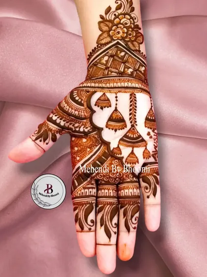 This is another take on the jhumka design, with an Arabic-style vine on the side of the hand. The hanging bells add a playful touch to the elegant floral and paisley patterns.
