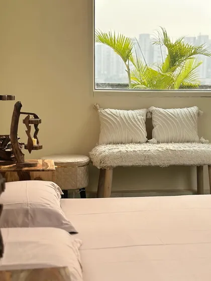 A peek into the cozy indoor studio. This corner features a boho-style bench and a window with a view of the green patio, blending the indoor and outdoor spaces.