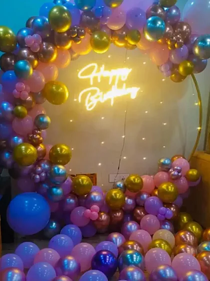 A vibrant birthday party decoration with a full ring of purple, pink, and gold balloons.