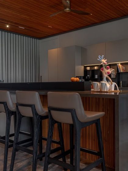 This kitchen in Ahmedabad, designed by DK Design Lab, is defined by architectural clarity. The layered island combines wood shelving with dark counters, creating a functional and visually interesting centerpiece.