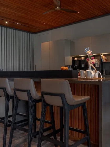 This kitchen in Ahmedabad, designed by DK Design Lab, is defined by architectural clarity. The layered island combines wood shelving with dark counters, creating a functional and visually interesting centerpiece.