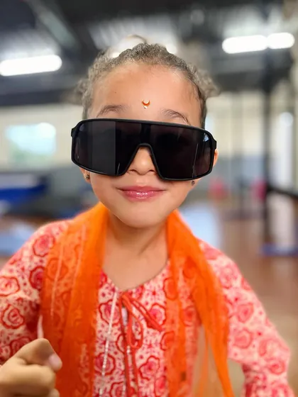 A close-up of our little star. The oversized sunglasses and confident smile capture the fun and playful vibe of our kids' program.