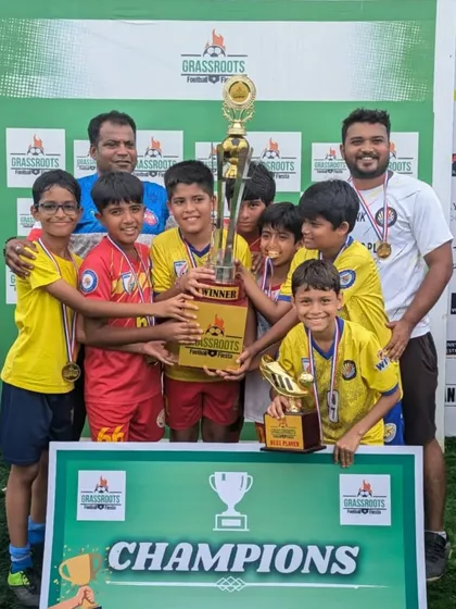 The U11 champions posing with their trophy and coaches at the Grassroots Football Fiesta.