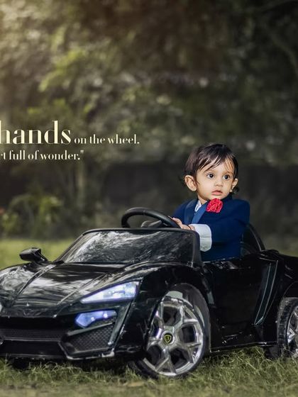 Tiny hands on the wheel, heart full of wonder. This dapper little boy is ready for a drive in his sleek toy car.