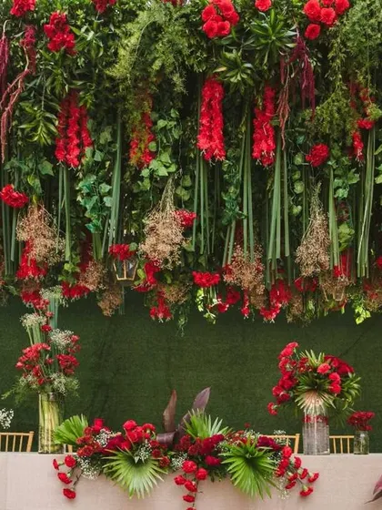 This angle showcases how the overhead installation and the table decor work together. The continuity of the red and green theme from the canopy to the centerpieces creates a cohesive and professionally styled environment.