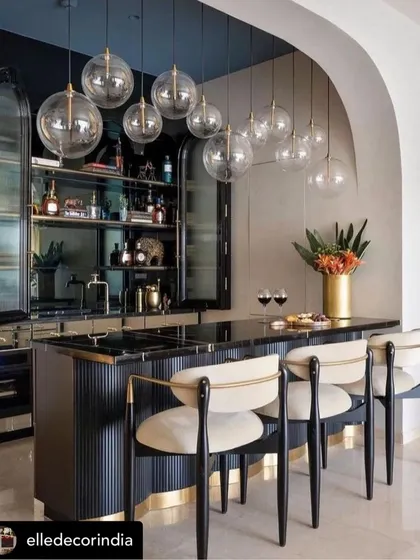 A sophisticated home bar we created, featured in Elle Decor. The design includes a fluted black bar counter, brass accents, and custom bar stools with black wood frames and cream upholstery.