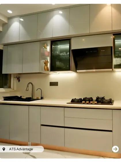 A sleek and modern kitchen with light grey glossy cabinets and a black countertop. The under-cabinet lighting provides excellent task illumination.