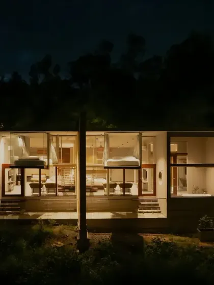 A close-up night view of the resort cottages, where the warm interior light reveals the minimalist design of the bedrooms within.
