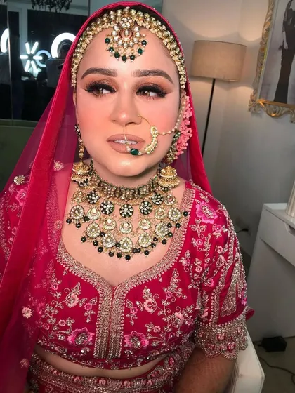 A beautiful bride in a pink lehenga, wearing a heavy polki and black bead necklace. The contrast is striking and modern.