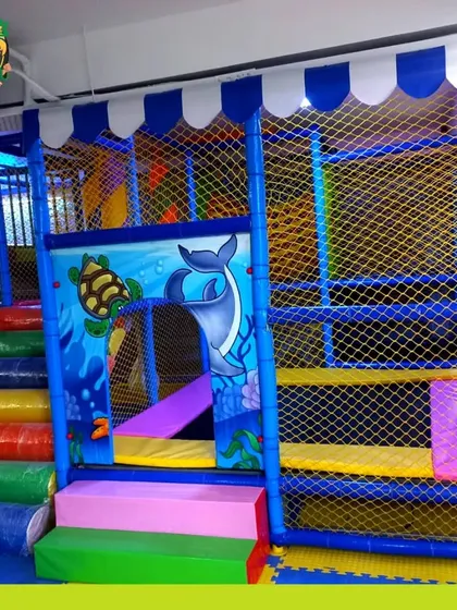 A view of the entrance to our soft play structure, featuring padded, colorful steps and aquatic-themed wall art, all enclosed by safety netting.