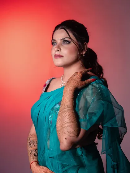 A stunning bridal portrait of Priya, using colored lighting to create a dramatic, editorial feel. This highlights her makeup, hairstyle, and the rich color of her saree.