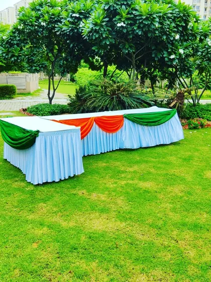 A buffet table decorated with saffron, white, and green fabric frills for an Independence Day lunch. Even the catering setup is themed to match the occasion.