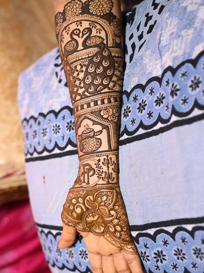 The completed arm design, featuring peacocks, a teapot, and the couple's initials.