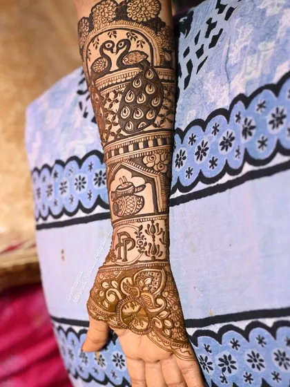 The completed arm design, featuring peacocks, a teapot, and the couple's initials.
