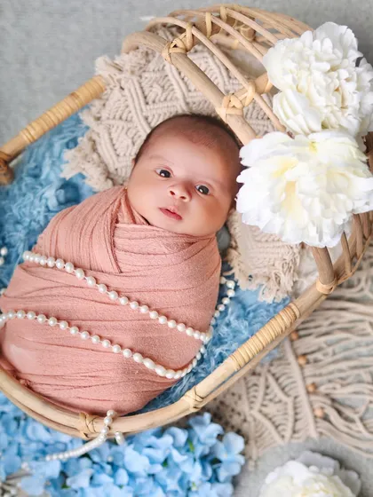 This shot captures the baby's gaze, creating a sweet and engaging portrait within the beautifully styled bassinet.