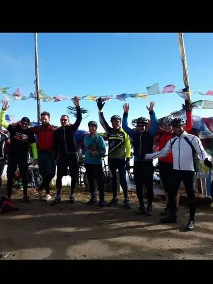 The team celebrating at a pass decorated with prayer flags in Bhutan. There's a great sense of shared achievement on our group tours.