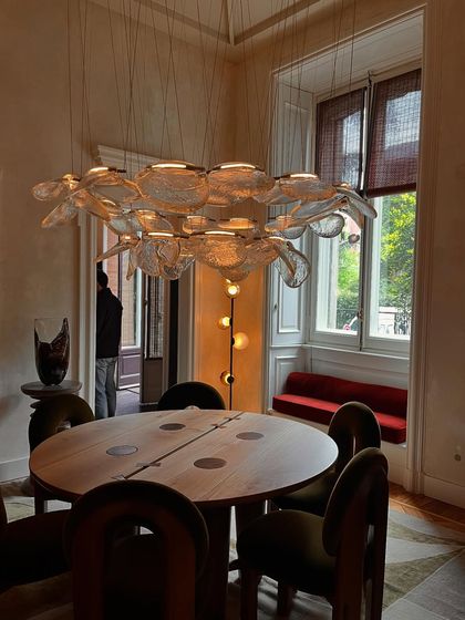 The Bocci 141 series installed as a grand chandelier over a dining table in a room with high ceilings and large windows.