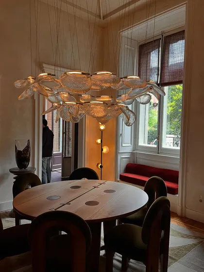 A grand installation of the Bocci 141 series forming a horizontal chandelier over a dining table. This demonstrates how individual elements can be composed into a large-scale, bespoke fixture.