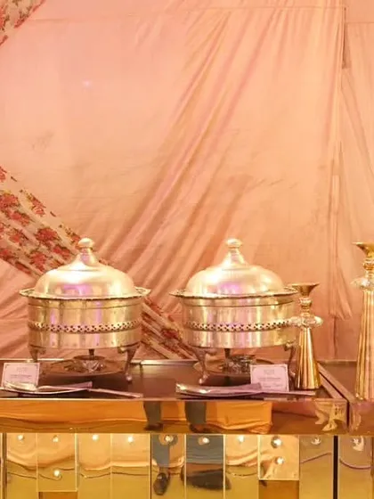 A close-up of the ornate, golden buffet counter featuring polished silver chafing dishes and tiered decorative stands.